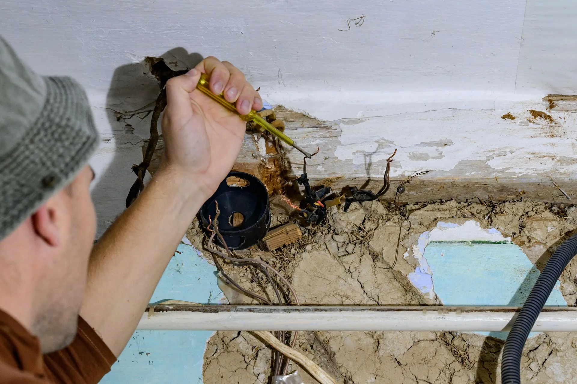 A man is measuring a hole in the wall with a tape measure.