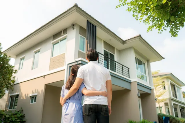 A man and a woman are standing in front of a house.